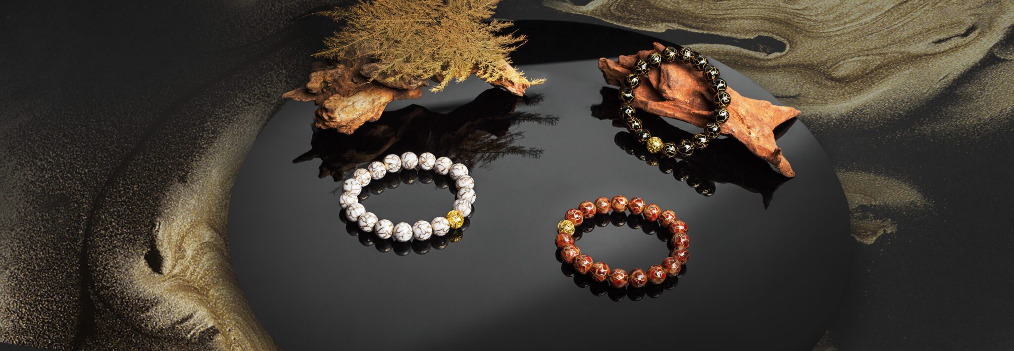 Trio of handcrafted Cloisonné enamel bracelets from Moke, featuring white, black, and red designs with gold accents. Styled with natural wood and textured lacquer background, these Asian-inspired accessories blend traditional Chinese artistry with modern elegance.